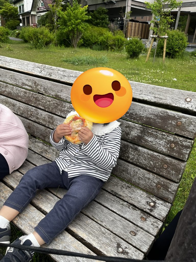 ベンチでベーカリー＆テーブルのピザパンを食べる娘