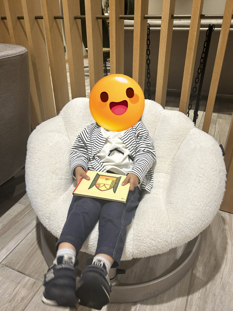 娘さんが絵本を持って椅子に座っている写真